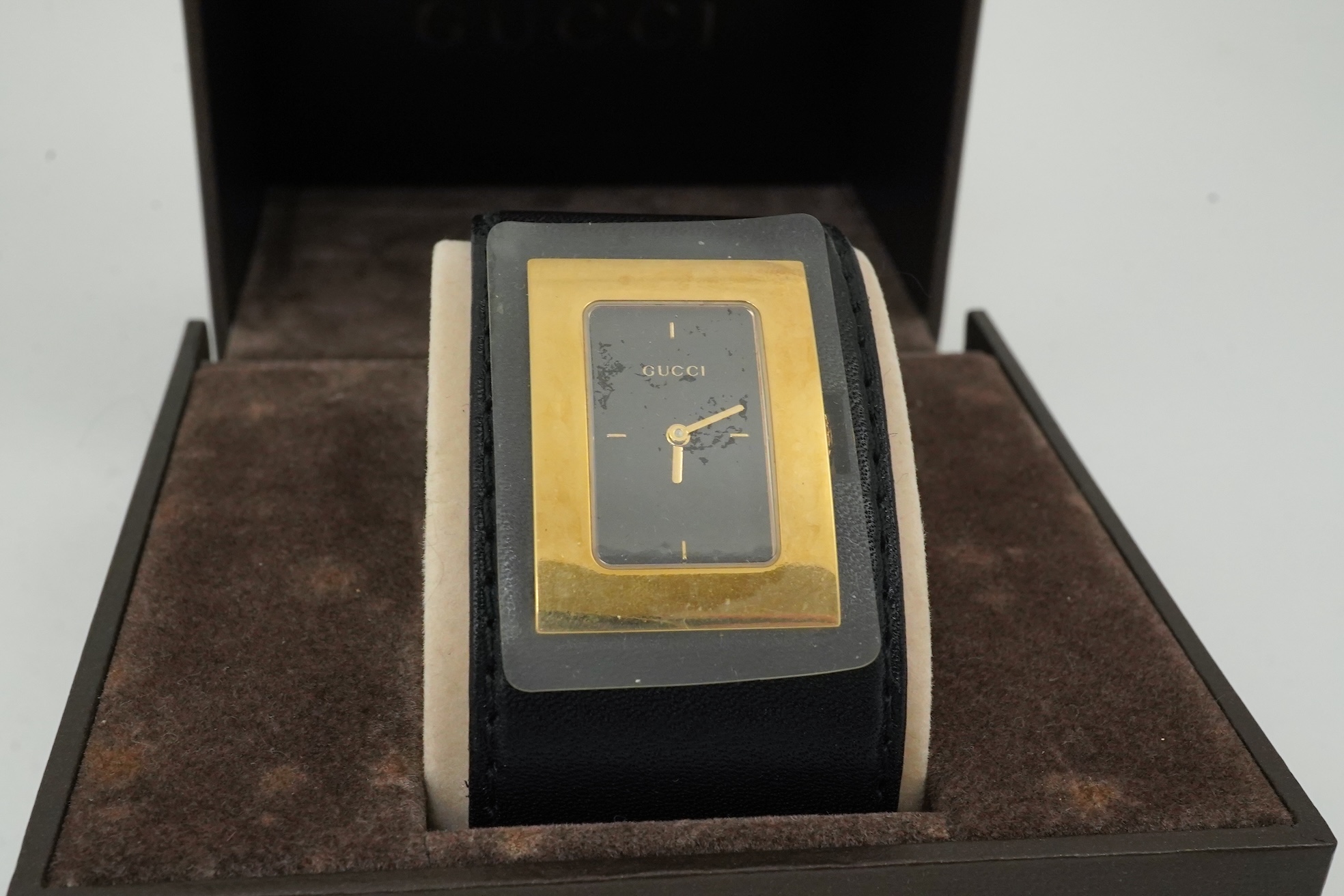 A lady's Gucci watch with wide leather strap, with box and papers.